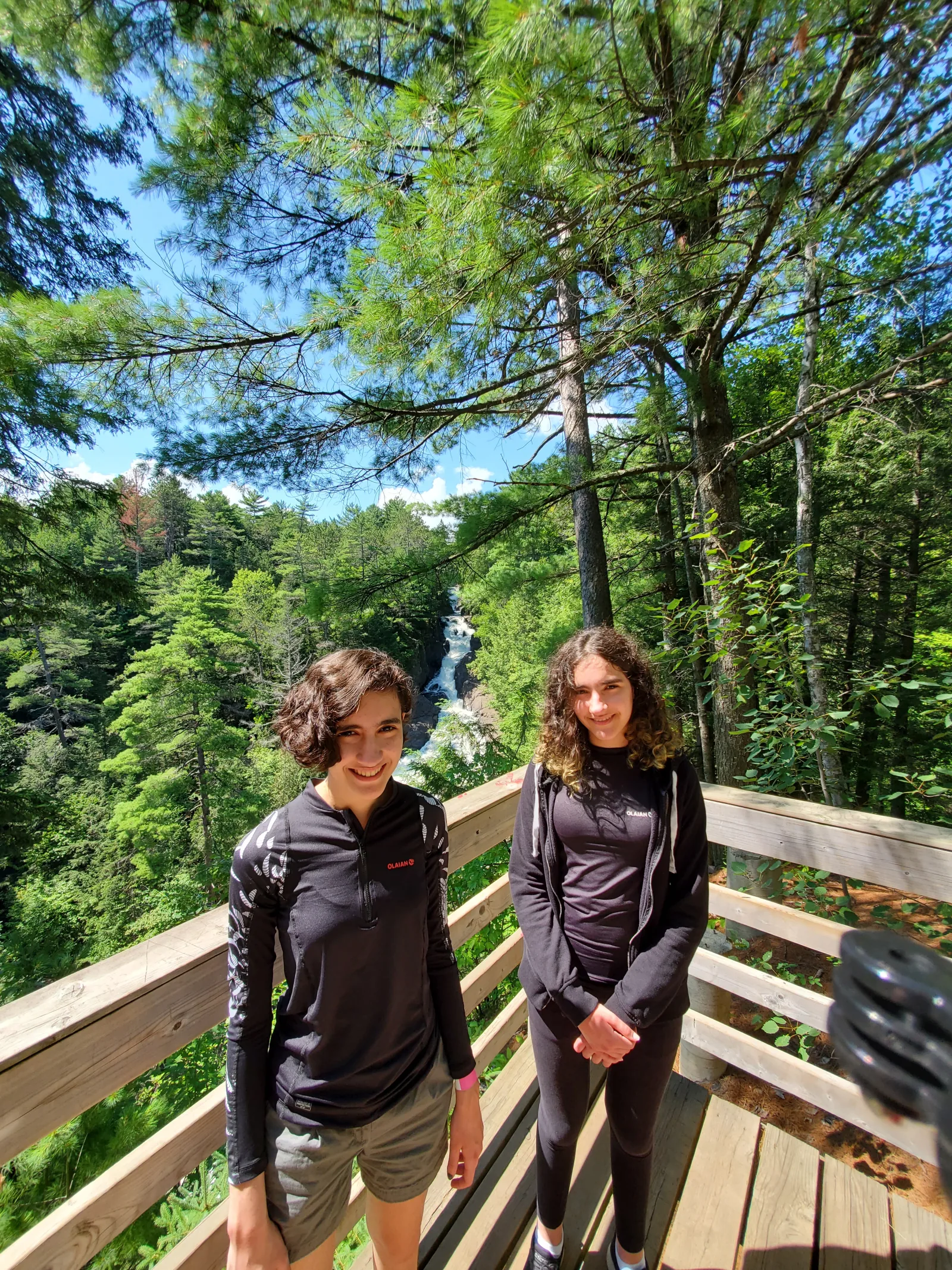 Duas adolescentes em mirante com uma cachoeira de Sainte-Ursule ao fundo